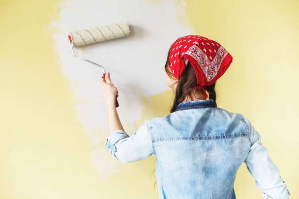 Menina bonita em vermelho Headband pintando a parede com rolo de tinta
 - Foto, Imagem