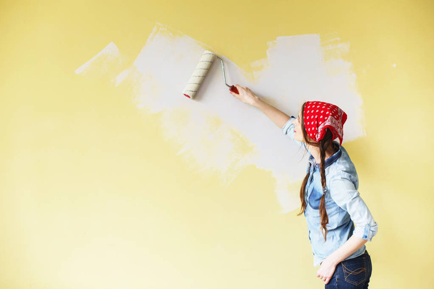 Menina bonita em vermelho Headband pintando a parede com rolo de tinta
 - Foto, Imagem