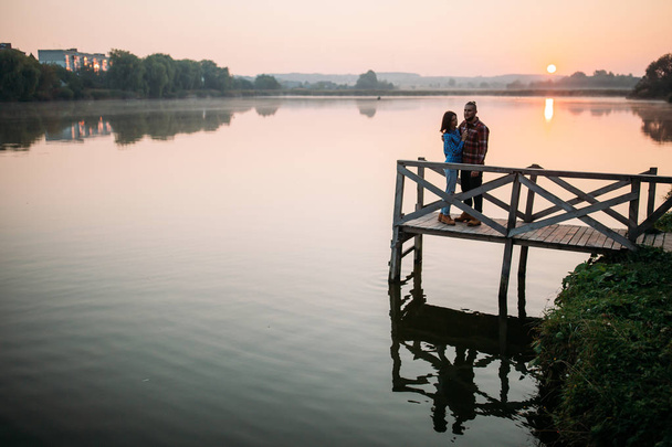 Cammina la mattina di un ragazzo e una ragazza. Una storia d'amore sul ponte. Giovani in riva al lago
. - Foto, immagini