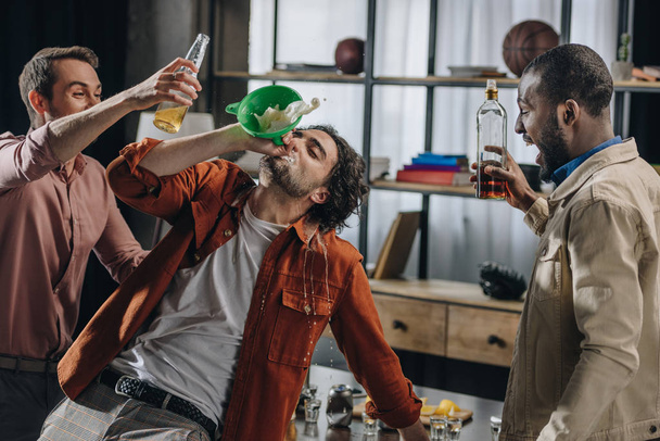 drunk male friends drinking alcohol beverages from funnel at party - Photo, Image