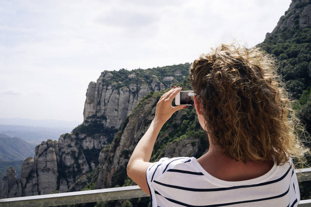 Young female hiker taking photo with smartphone at mountain peak  - Fotó, kép