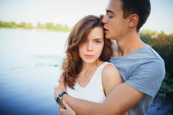 Handsome young man kissing his girlfriend near the river - Photo, Image