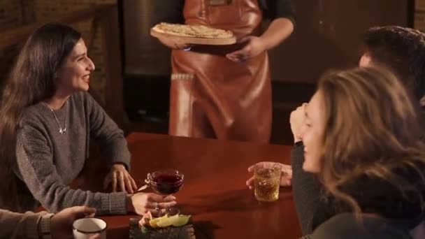 Σερβιτόρος φέρνει την πίτσα σε μια ομάδα - Πλάνα, βίντεο