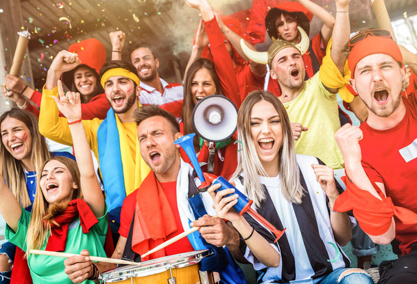 Football supporter fans friends cheering and watching soccer cup match at intenational stadium - Young people group with multicolored t-shirts having excited fun on sport world championship concept - Photo, Image