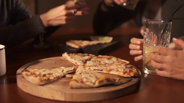 primer plano de la mesa con pizza, vasos, la gente está sentada en sillas
 - Imágenes, Vídeo