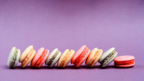 Sweet and colourful french macaroons or macaron on the purple background - Photo, image