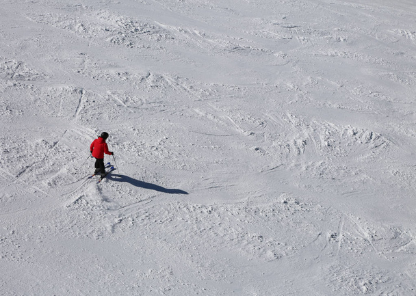 Ένας σκιέρ στην πλαγιά με χιόνι με κόκκινα ρούχα - Φωτογραφία, εικόνα