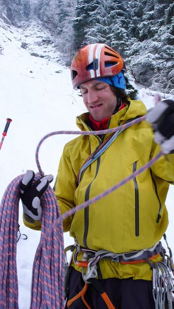彼はスイスのアルプスの急な氷の秋を登る前に男性の山岳ガイドが彼のギアを準備します。 - 写真・画像