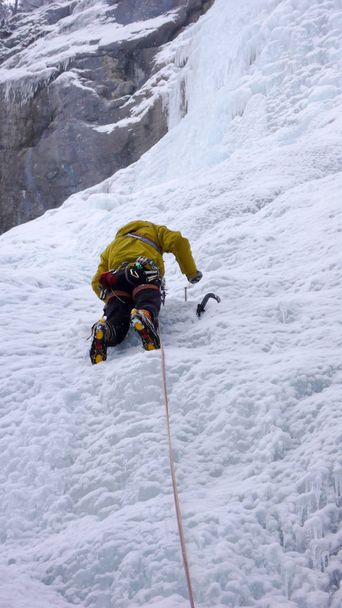 guía de montaña masculino escalando una empinada cascada congelada en un frío día de invierno en los Alpes
 - Foto, Imagen