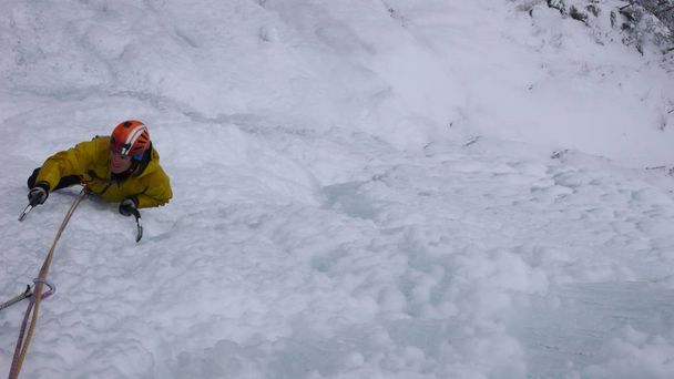 férfi túravezető mászni a meredek, fagyott vízesés egy hideg téli napon az Alpokban - Fotó, kép