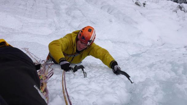 guide de montagne mâle escalade une cascade abrupte gelée par une journée froide d'hiver dans les Alpes
 - Photo, image