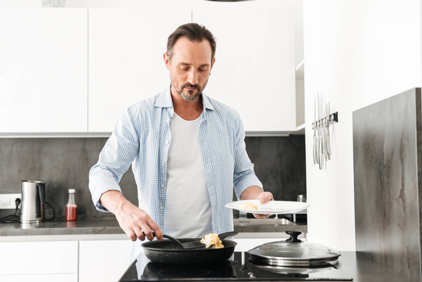 Confident mature man cooking breakfast - Foto, afbeelding