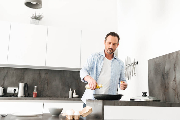 Confident mature man cooking breakfast - Photo, image