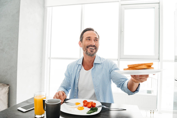 Smiling mature man passing a plate - Foto, afbeelding