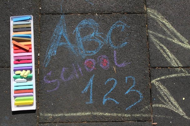 Школа, ABC и 123 вздоха написаны цветными мелом на тротуаре. Возвращение в школу на асфальте. и концепция отпуска. Концепция образования. Школа и веселье. Нет резкости
.  - Фото, изображение