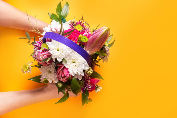 Woman hands pass bouquet, yellow background, copy space - Photo, image
