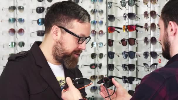 Optometrista professionista che mostra occhiali in vendita al suo cliente maschile
 - Filmati, video
