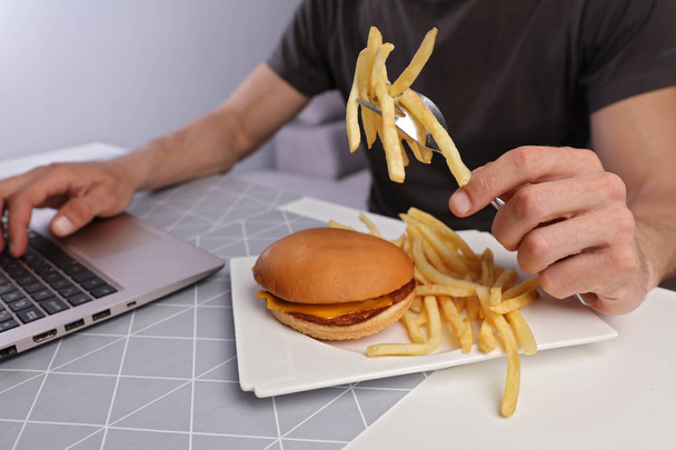 Overworked Business man eating hamburger / junk food for diner close up - 写真・画像