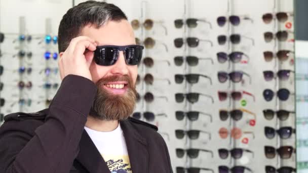 Cheerful mature man smiling to the camera while buying sunglasses - Footage, Video