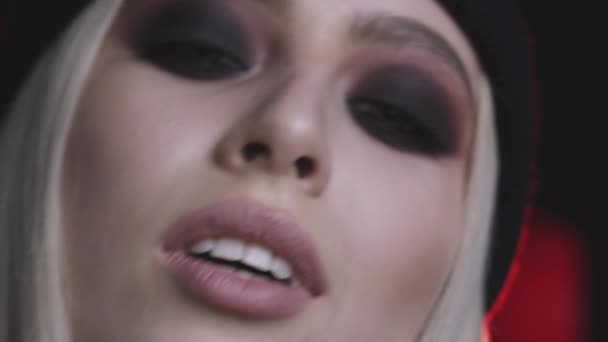 Close-up view of gorgeous young woman with smokey eyes makeup on dark background  - Filmagem, Vídeo