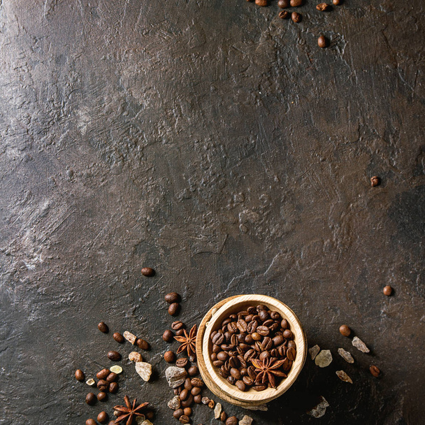 Різноманітність кавових зерен, коричневого цукру, спецій у дерев'яних мисках на фоні темної текстури. Вид зверху, місце для копіювання. Зображення квадрату
 - Фото, зображення