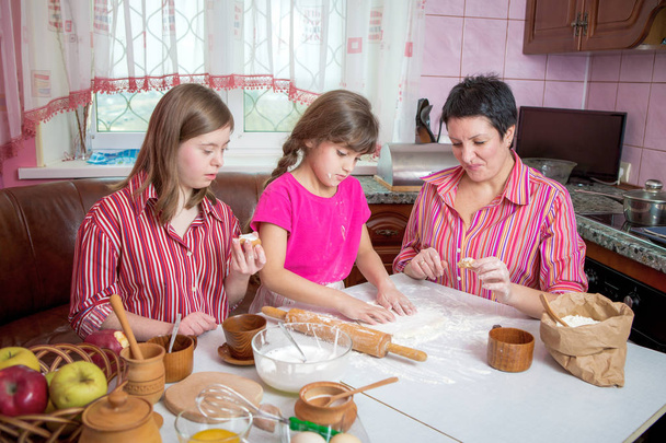 Mamma insegna alle sue due figlie a cucinare in cucina
. - Foto, immagini