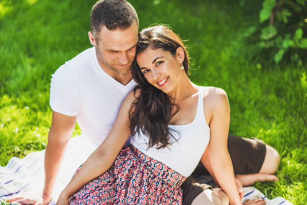Portrait of cute couple in love sitting on a picnic blanket outd - Фото, зображення