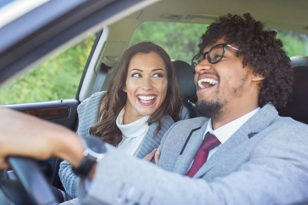 Happy young couple driving in a car while smiling and laughing - Photo, Image