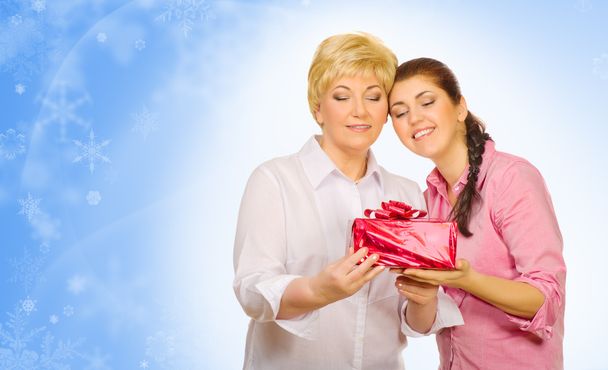 Young girl giving gift to her mother on winter background - Photo, image