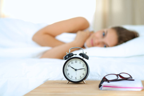 A young woman putting her alarm clock off in the morning - Foto, Imagen
