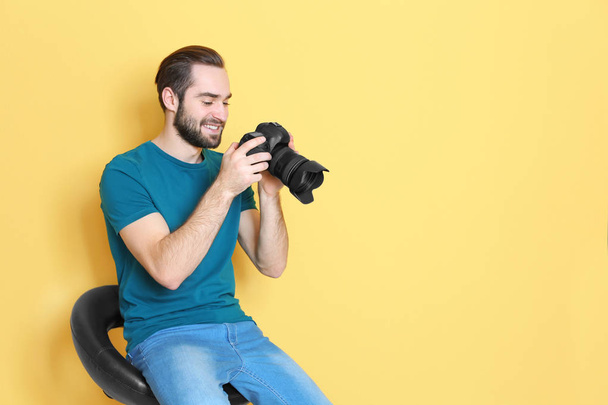 Young photographer with professional camera on color background - Foto, immagini