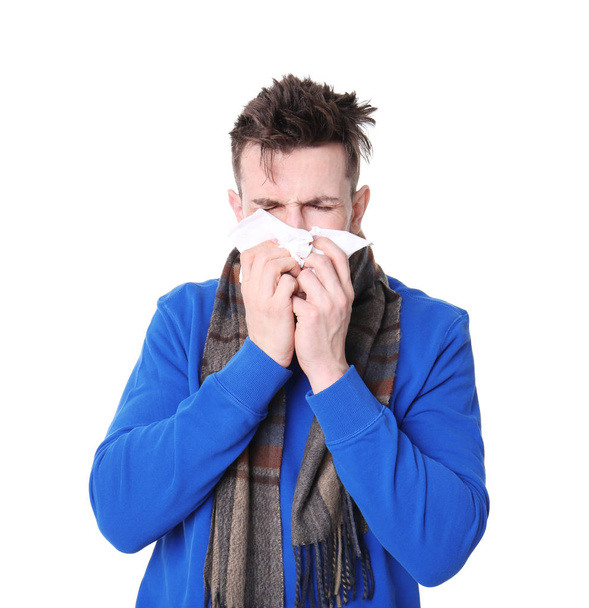 Young man with cold sneezing on white background - 写真・画像