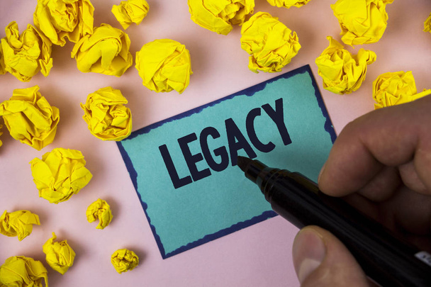Word writing text Legacy. Business concept for Transmitted Received from an ancestor Money Properties given by will written by Man on Sticky note paper holding Marker plain background Paper Balls. - Photo, Image