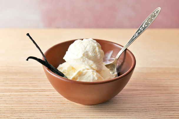 Bowl with tasty vanilla ice cream on wooden table - Valokuva, kuva