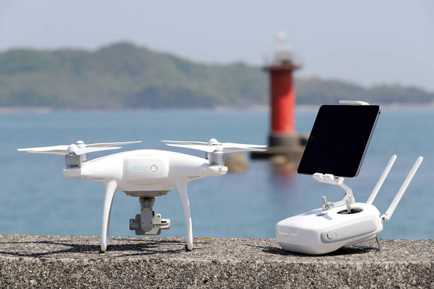 drone e controlador remoto com monitor em molhe de concreto
  - Foto, Imagem