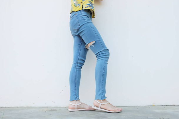 Summer Fashion Nude Sandal (Footwear) and Slim Legs in The City,Street Style. Beautiful Slim Woman Legs with Nude Sandals and Lack Blue Jean on Concrete Floor Background - Photo, Image