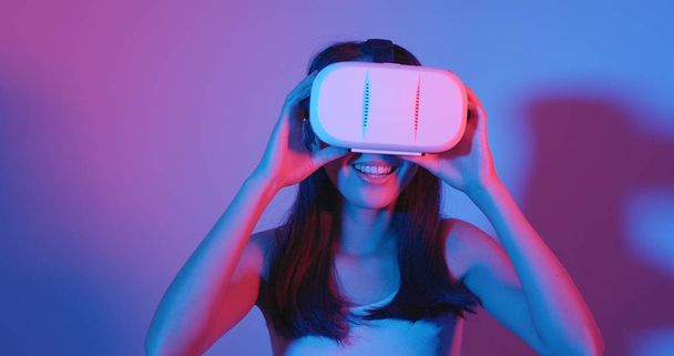 Женщина смотрит через VR гарнитуру
 - Фото, изображение