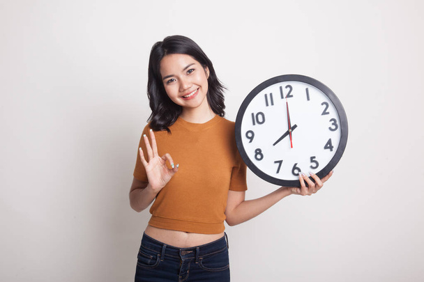 Young Asian woman show OK with a clock. - Foto, imagen