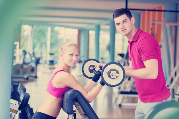 young sporty woman with trainer exercise weights lifting in fitness gym - Photo, image