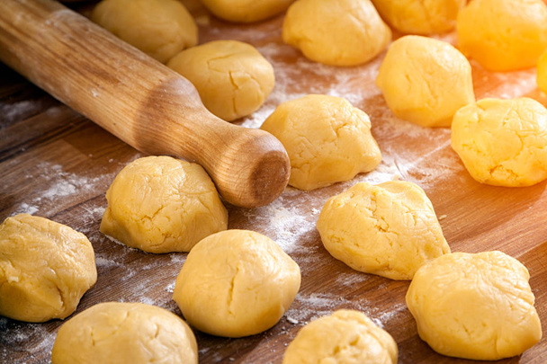 Un gros plan sur le processus de cuisson des petits pains ou des crêpes, à côté est un rouleau à pâtisserie en bois avec de la farine sur une table en bois
 - Photo, image