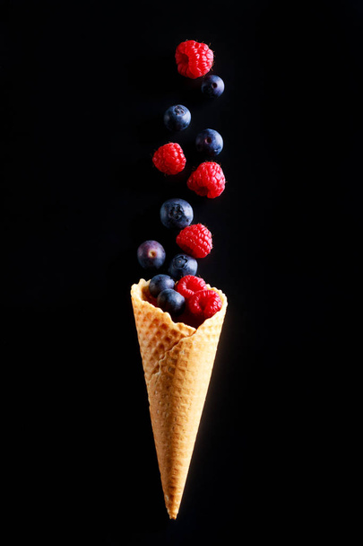 Concept of fresh fruit as alternative to ice cream. Berries fruits spill out of crispy cones wafers. - Zdjęcie, obraz