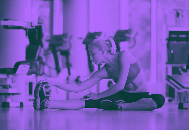 Cute young woman stretching and warming up for her training at a gym duo tone - Valokuva, kuva