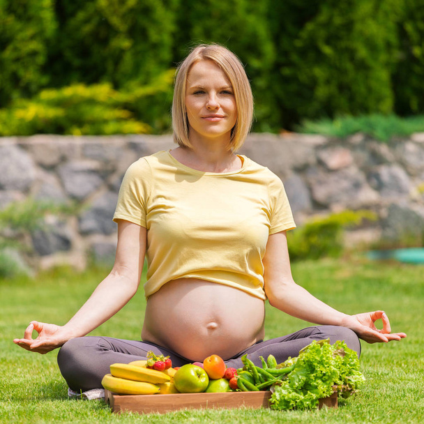 Pregnant woman practicing meditation and relaxation in nature - Fotó, kép