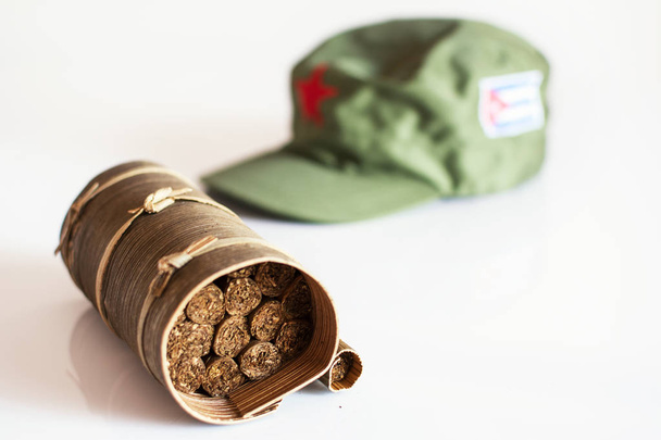 Cuban cigars rolled in banana leaf and military cap on the backg - Photo, Image