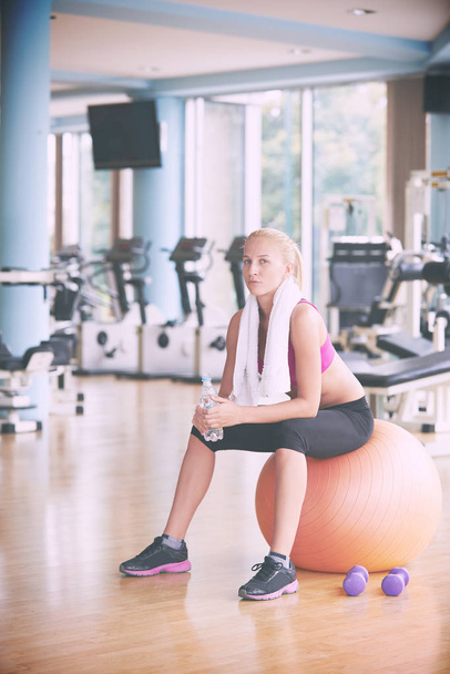 young healthy blonde woman drinking water  in fitness gym while sitting on pilates ball - Foto, immagini