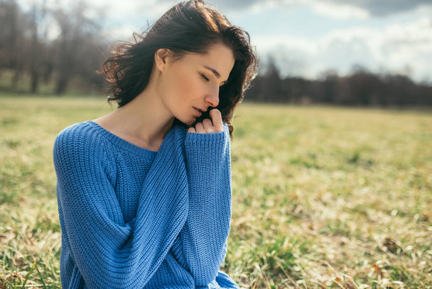 Portrait of dreamy female with closed eyes with hand on face. Attractive brunette caucasian young woman with windy hair outside, on spring or on summer, in park. Lifestyle fashion concept. Cover idea. - Φωτογραφία, εικόνα