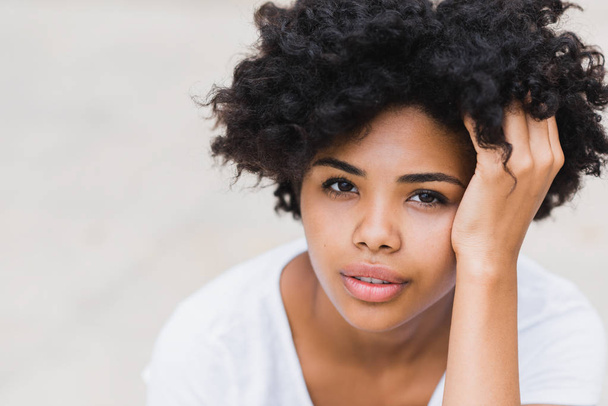 Close-up portait of beautiful young black woman with sad, pensive, reflective look, against white wall background with copy space for your text or advertising content.  - Photo, Image