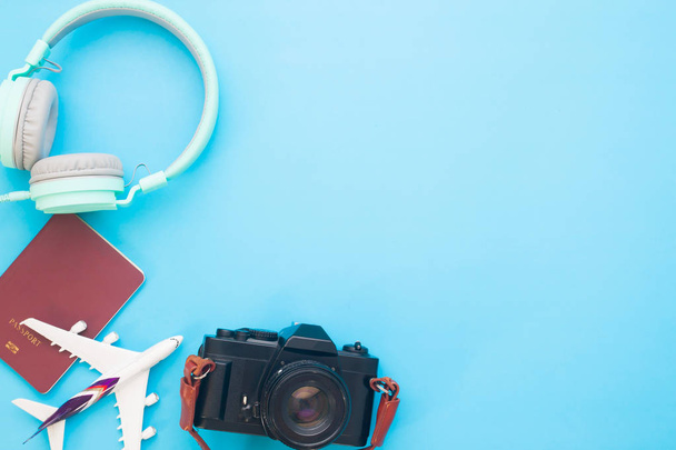 Concepto creativo de viaje plano con auriculares, pasaporte, modelo de avión y cámara en fondo de color azul con espacio de copia
 - Foto, Imagen