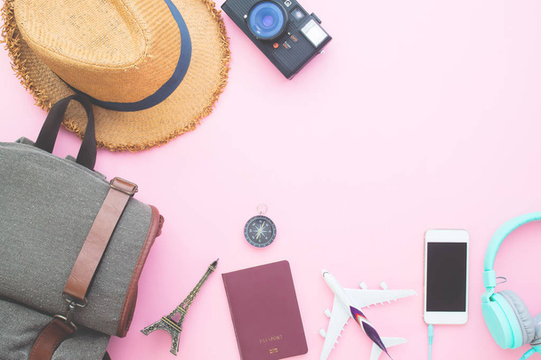 Creative flat lay backpack suitcase, passport, smart phone, camera and headphones on pink color background - Photo, image