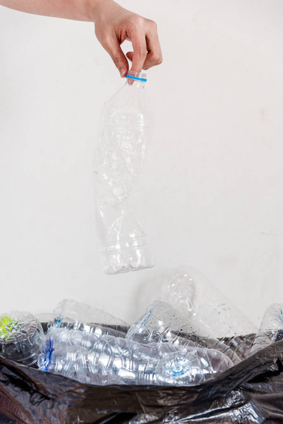Plastic flessen in zwarte vuilniszakken wachten te worden genomen om te recyclen. - Foto, afbeelding